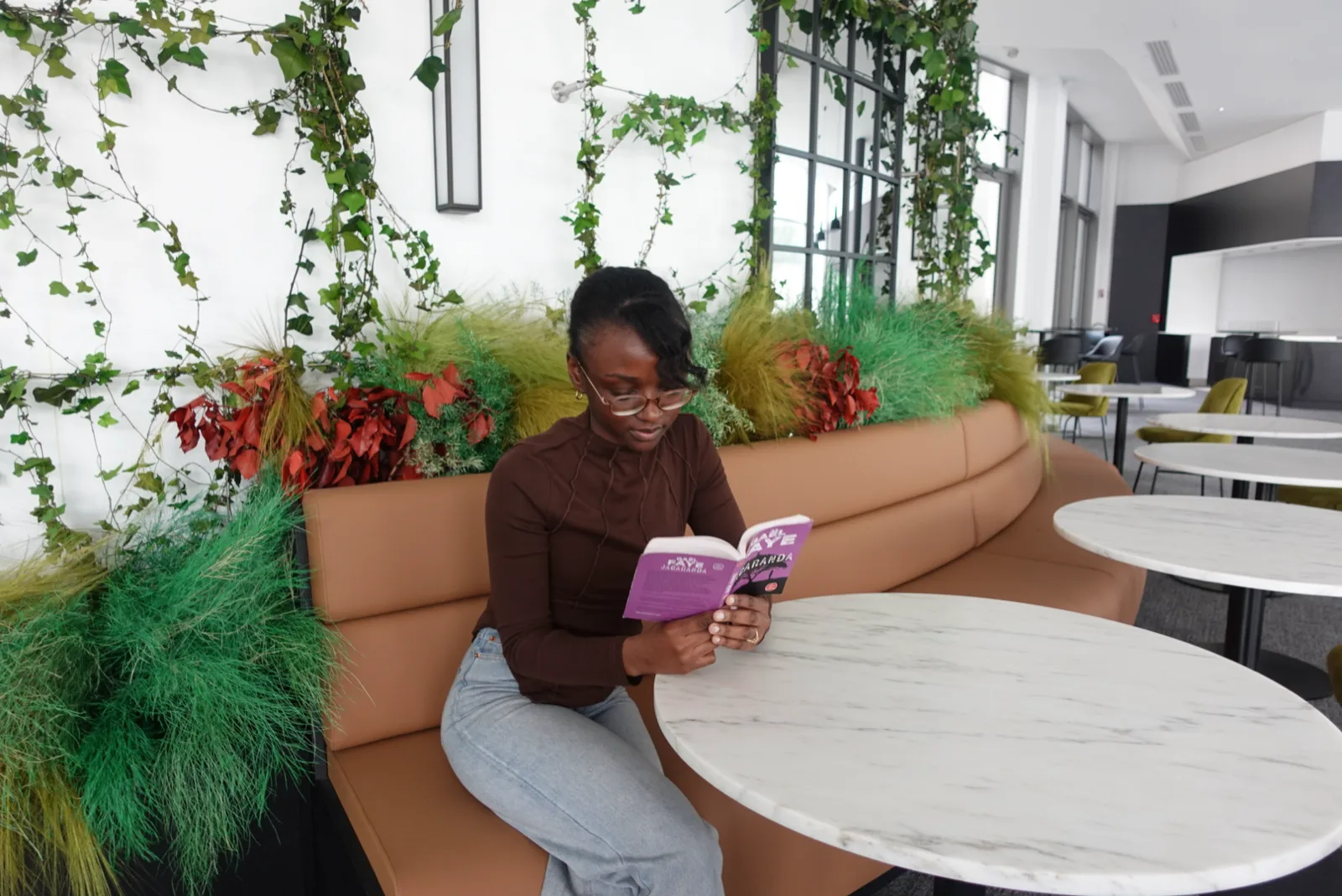 Divine, un livre ouvert entre les mains, dans un salon lumineux