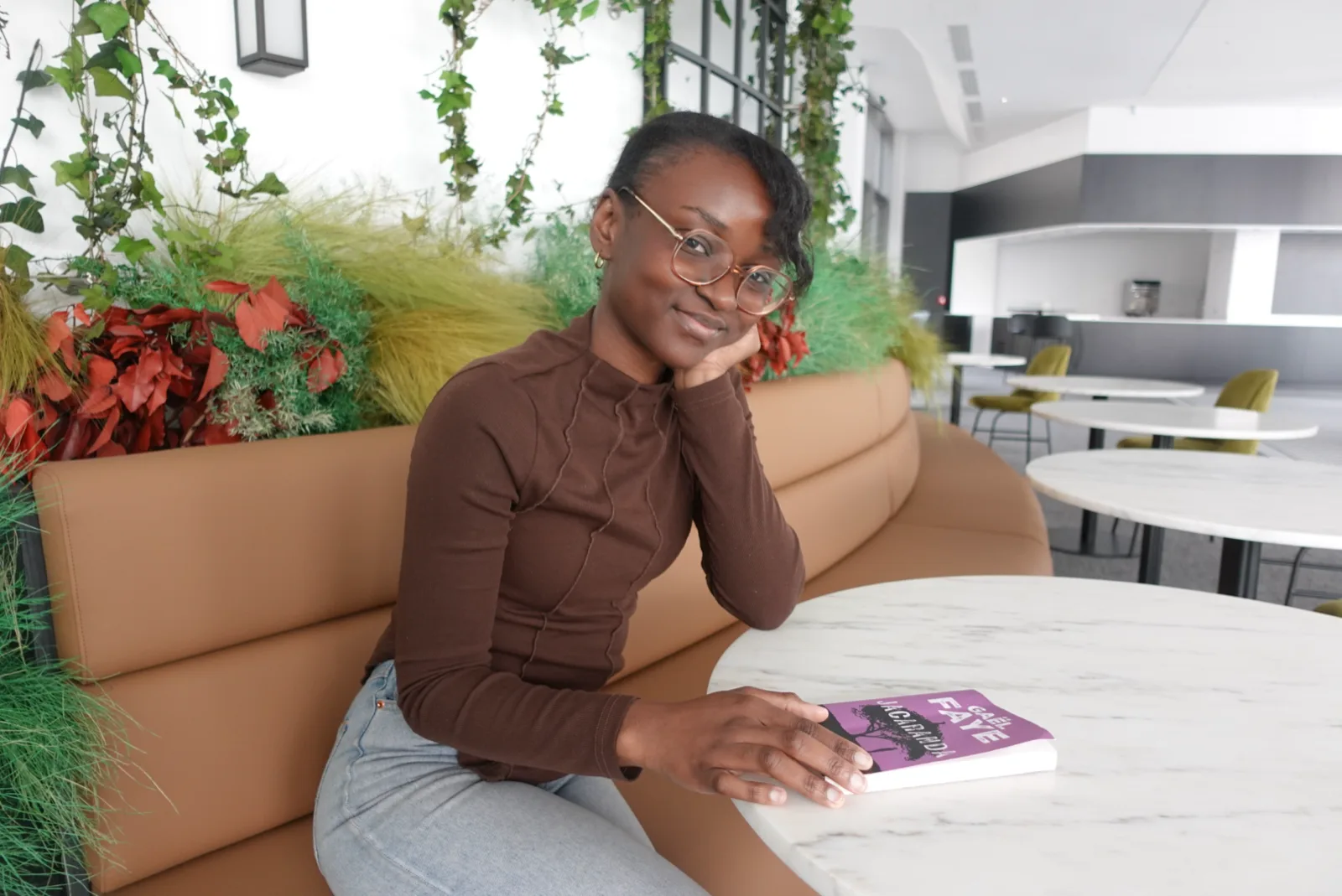 Divine, fondatrice du Club Yada, attablée avec un livre dans un café lumineux