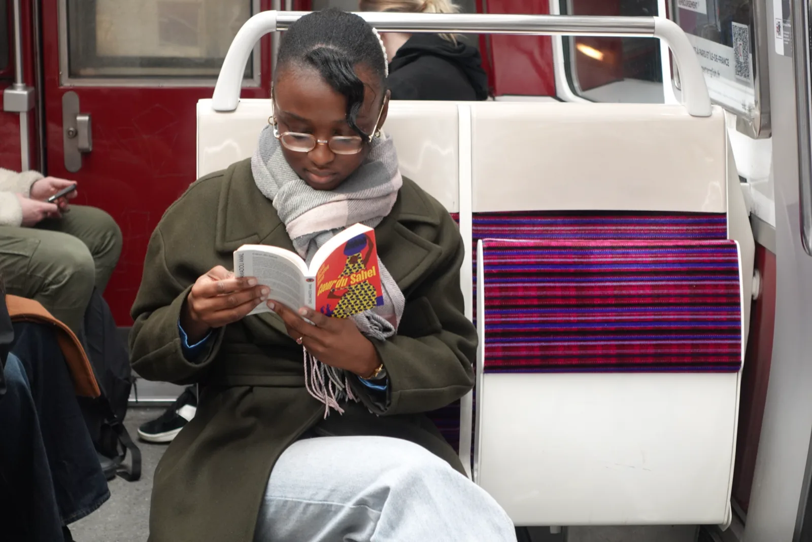 Une lectrice plongée dans un roman, assise dans une rame de métro